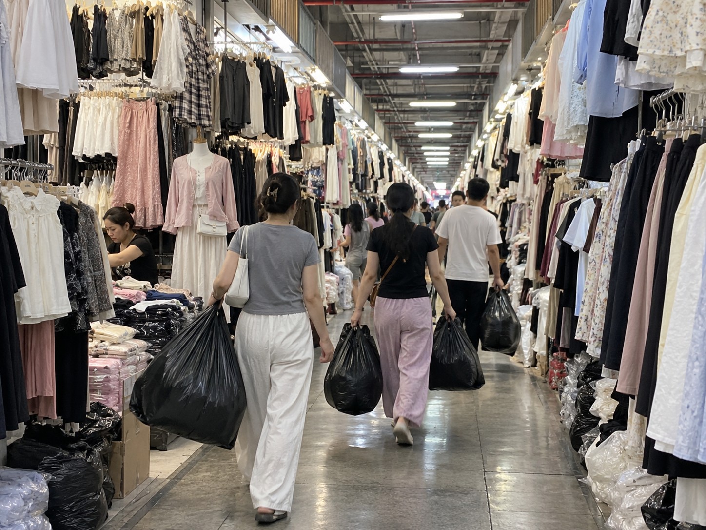 服装城楼层通道里提着货的客人
